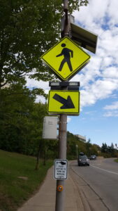 solar powered pedestrian walk sign next to busy highway